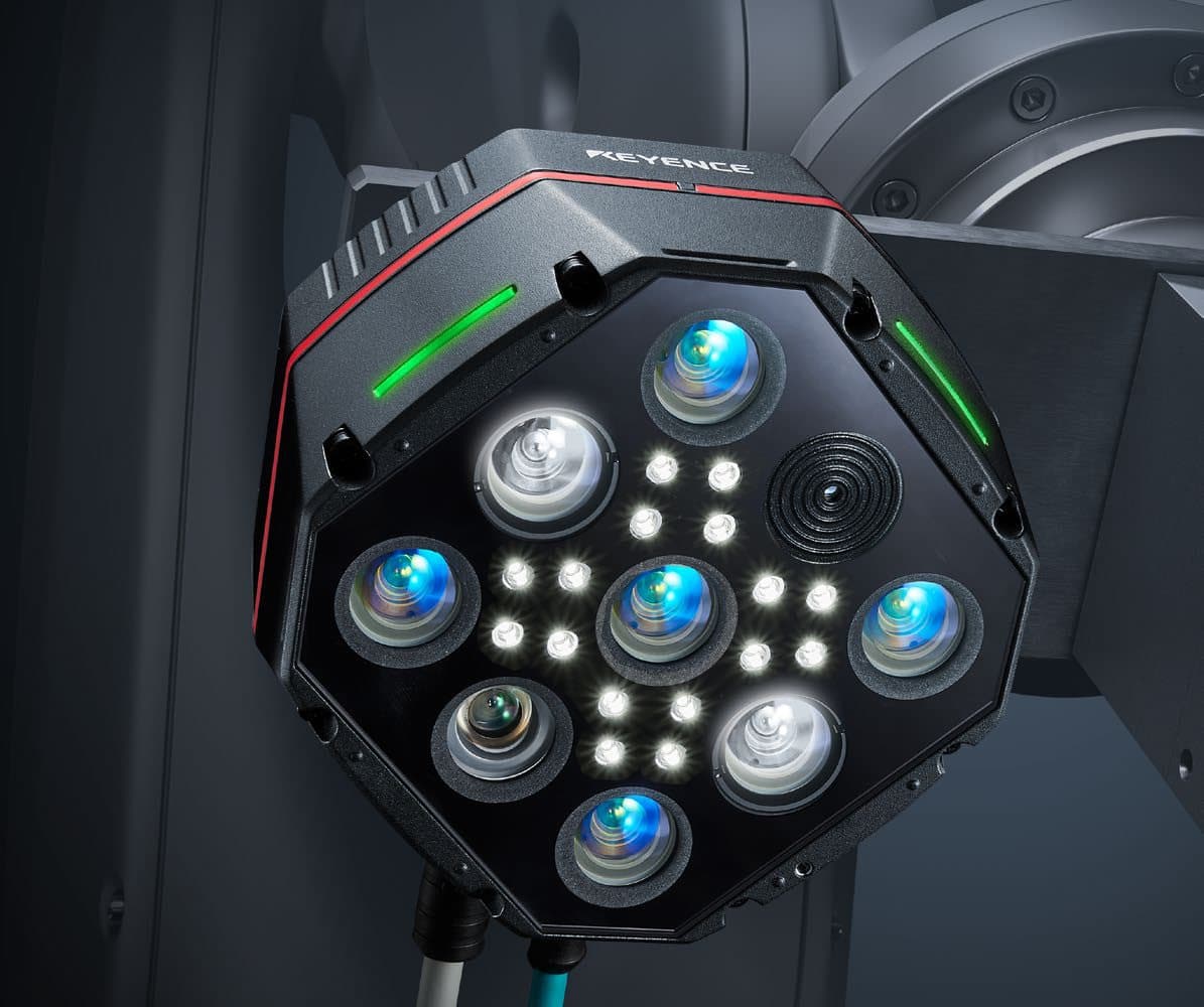 The Keyence CG-R camera mounted on a robot: five blue lenses, a darker lens, two large white lenses and rings of LEDs on a black octagonal face
