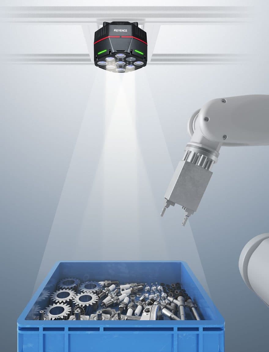 A CG-R camera on an overhead rail, lighting a bin of gears and spark plugs while a robot gripper waits beside it